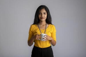 pretty young girl with a cup of tea or coffee posing on grey background photo