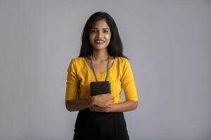 Young girl using mobile phone or smartphone on gray background photo