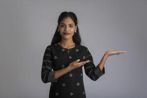 Beautiful girl holding and presenting something in the hand with a happy smiling face. photo