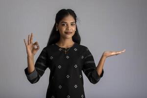 Beautiful girl holding and presenting something in the hand with a happy smiling face. photo