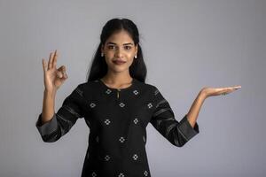 Beautiful girl holding and presenting something in the hand with a happy smiling face. photo
