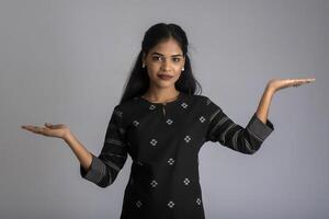 Beautiful girl holding and presenting something in the hand with a happy smiling face. photo