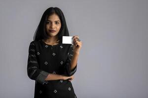 Young smiling beautiful woman or girl presenting credit card in hand showing trust and confidence for making payment. photo
