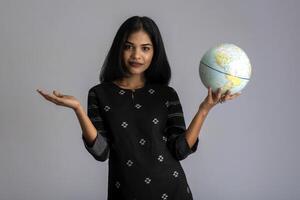 young girl holding the world globe and posing on a grey background. photo