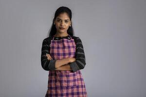 Portrait of Indian woman chef or cook in an apron on grey background. photo