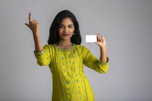 Young smiling beautiful girl posing with a credit card on grey background. photo