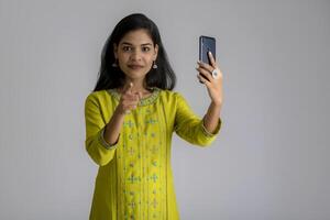 Young girl using mobile phone or smartphone on gray background photo