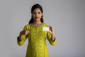 Young smiling beautiful girl posing with a credit card on grey background. photo