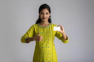Young smiling beautiful girl posing with a credit card on grey background. photo