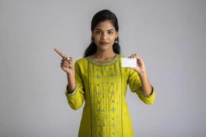 Young smiling beautiful girl posing with a credit card on grey background. photo