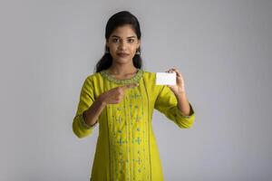 Young smiling beautiful girl posing with a credit card on grey background. photo