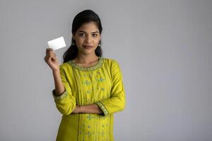 Young smiling beautiful girl posing with a credit card on grey background. photo