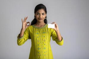 Young smiling beautiful girl posing with a credit card on grey background. photo