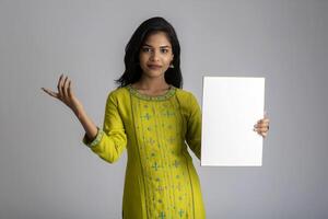 A young girl or businesswoman holding a signboard in her hands on a gray background. photo