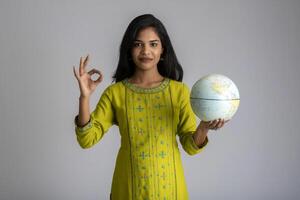 young girl holding the world globe and posing on a grey background. photo