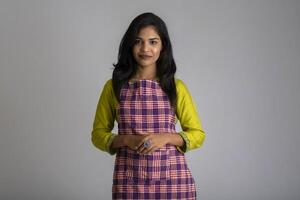 Portrait of Indian woman chef or cook in an apron on grey background. photo