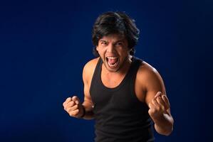 Portrait of a young man posing and showing his muscular body. The concept of a healthy lifestyle on blue background. photo