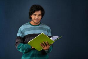 Young happy man holding and posing with the book on background. photo
