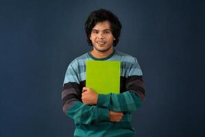 Young happy man holding and posing with the book on background. photo
