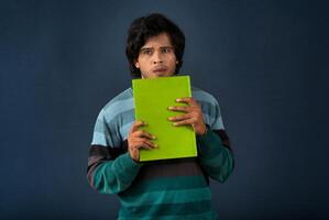 Young happy man holding and posing with the book on background. photo