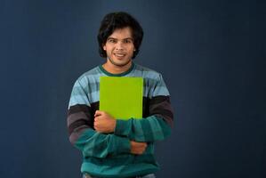 Young happy man holding and posing with the book on background. photo