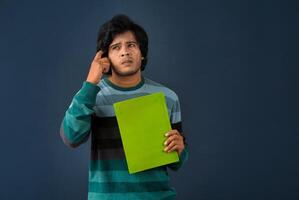 Young happy man holding and posing with the book on background. photo