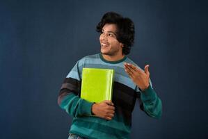 Young happy man holding and posing with the book on background. photo