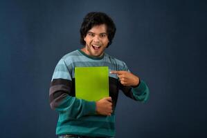 Young happy man holding and posing with the book on background. photo