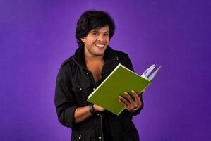 Young happy man holding and posing with the book on background. photo
