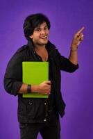 Young happy man holding and posing with the book on background. photo