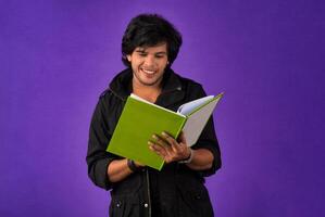 Young happy man holding and posing with the book on background. photo