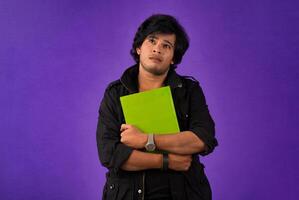 Young happy man holding and posing with the book on background. photo