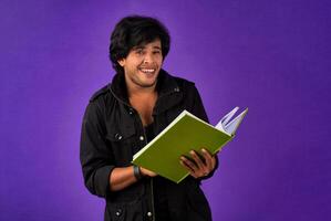 Young happy man holding and posing with the book on background. photo