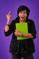 Young happy man holding and posing with the book on background. photo