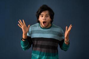 Young handsome man over dark background afraid and shocked with surprise and amazed expression, fear and excited face. photo
