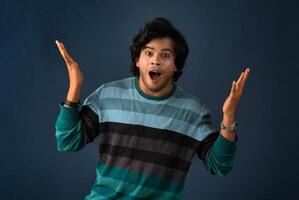 Young handsome man over dark background afraid and shocked with surprise and amazed expression, fear and excited face. photo