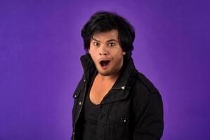 Young handsome man over dark background afraid and shocked with surprise and amazed expression, fear and excited face. photo