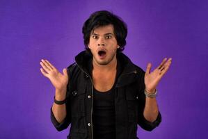 Young handsome man over dark background afraid and shocked with surprise and amazed expression, fear and excited face. photo