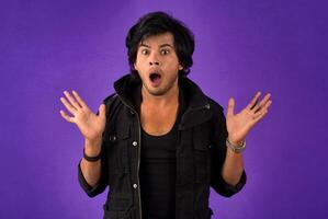 Young handsome man over dark background afraid and shocked with surprise and amazed expression, fear and excited face. photo