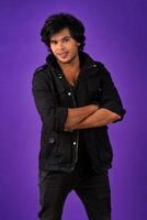Portrait of Happy Indian young man with arms crossed against a dark background photo