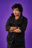 Portrait of Happy Indian young man with arms crossed against a dark background photo