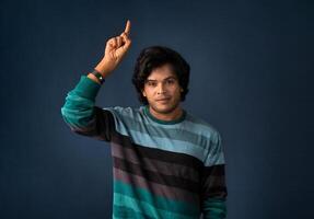 Portrait of a successful cheerful young man pointing and presenting something with hand or finger with a happy smiling face. photo