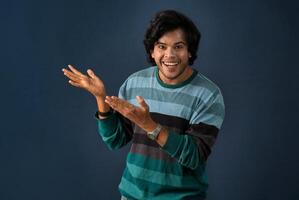 Portrait of a successful cheerful young man pointing and presenting something with hand or finger with a happy smiling face. photo
