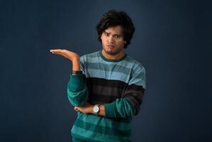 Portrait of a successful cheerful young man pointing and presenting something with hand or finger with a happy smiling face. photo