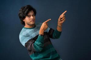 Portrait of a successful cheerful young man pointing and presenting something with hand or finger with a happy smiling face. photo