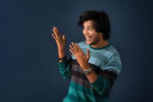 Portrait of a successful cheerful young man pointing and presenting something with hand or finger with a happy smiling face. photo