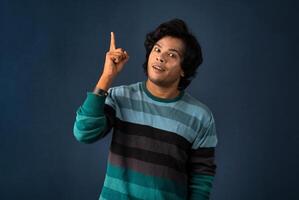 Portrait of a successful cheerful young man pointing and presenting something with hand or finger with a happy smiling face. photo