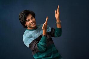 Portrait of a successful cheerful young man pointing and presenting something with hand or finger with a happy smiling face. photo