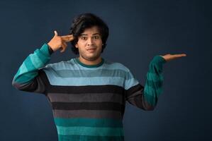 Portrait of a successful cheerful young man holding and presenting something on hand with a happy smiling face. photo