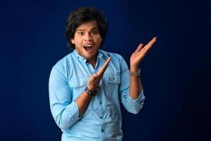 Portrait of a successful cheerful young man pointing and presenting something with hand or finger with a happy smiling face. photo